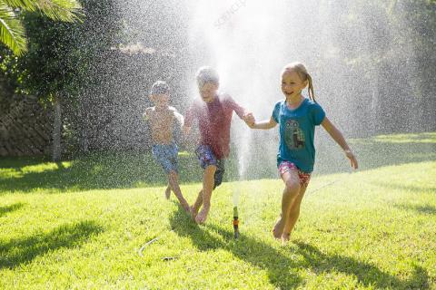 kids running through a sprinkler
