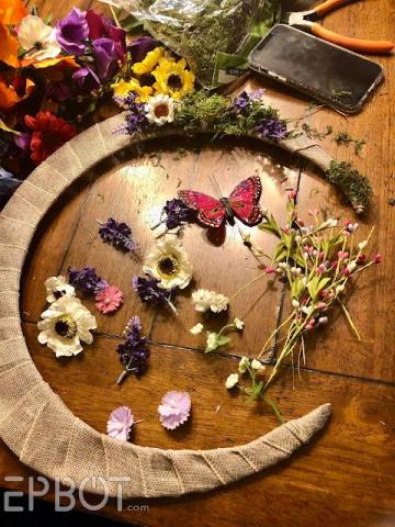 crescent shaped wreath covered with burlap and decorated with flowers