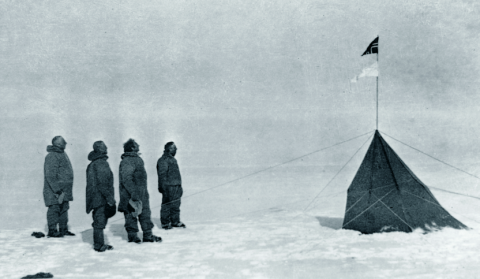 old black and white photo of 4 men and tent in snowy environment