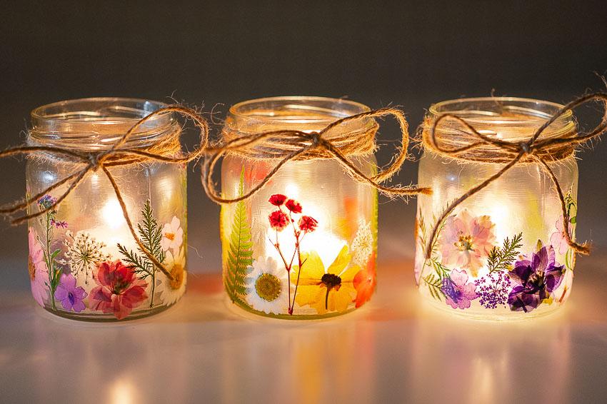 small jars with pressed flowers and a lit candle