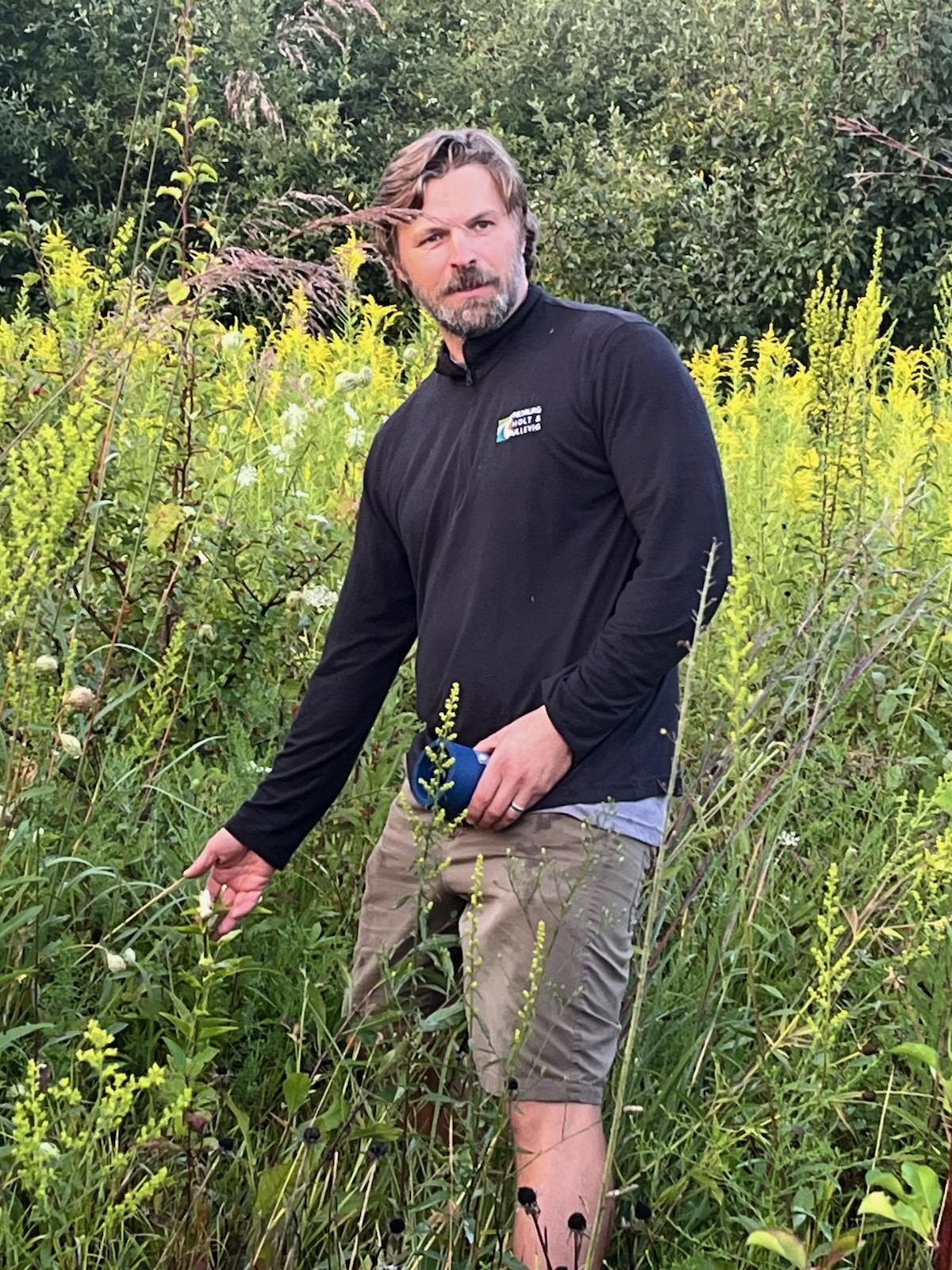 Jake Llyed standing in a field of native wildflowers